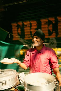 Smiling vendor in Dharamshala offering fresh dumplings outdoors. Vibrant street food scene.