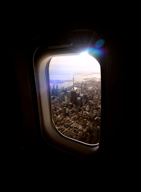 Stunning aerial view of Toronto cityscape through an airplane window at sunset.