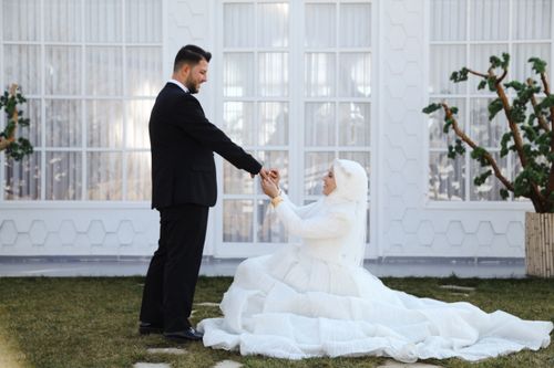 Free A bride and groom hold hands outside in a lush garden during their wedding ceremony. Stock Photo