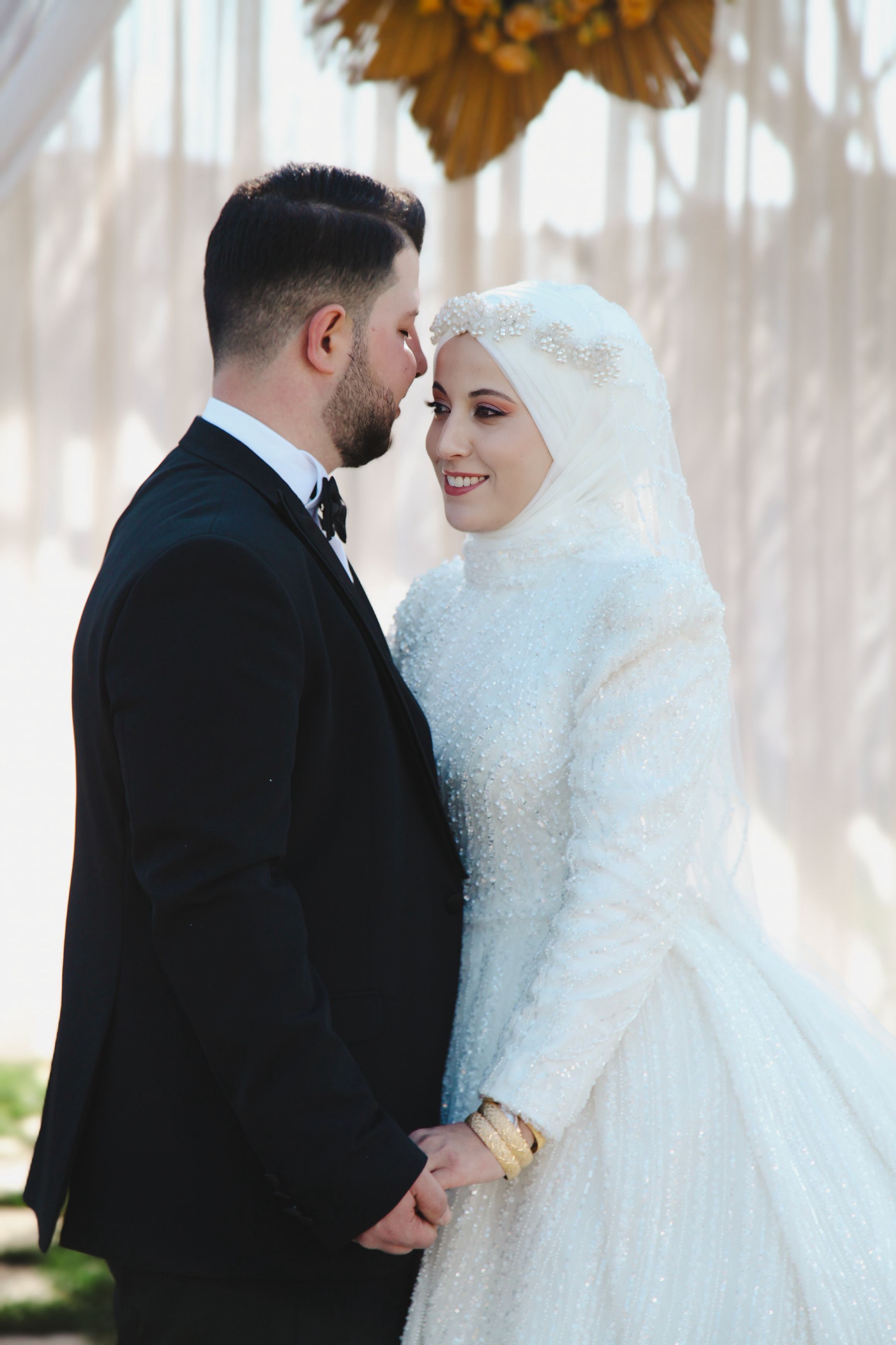 Bride and groom embracing in elegant outdoor wedding ceremony.