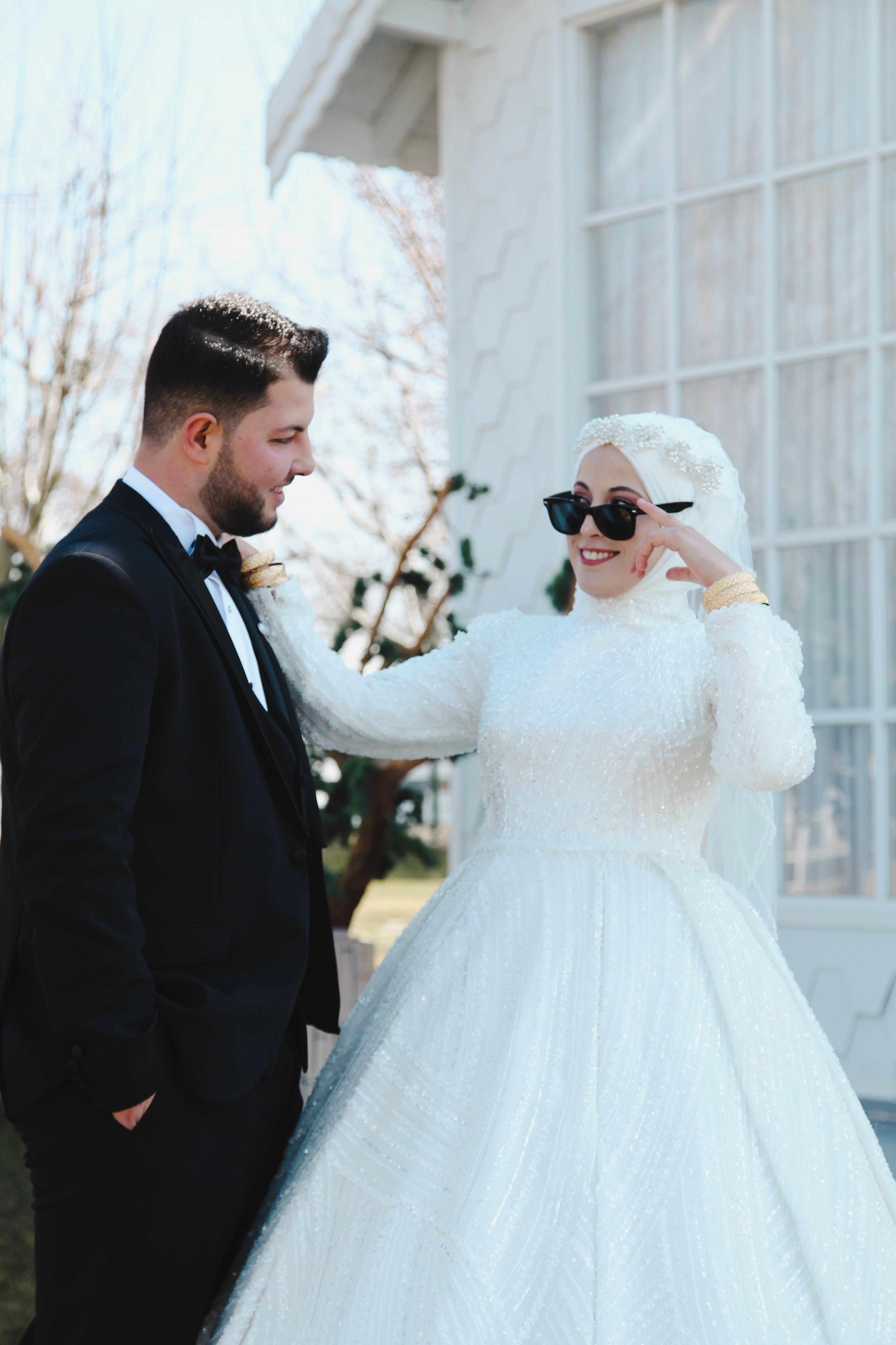 Bride and groom in classic wedding attire enjoying a sunny outdoor moment.