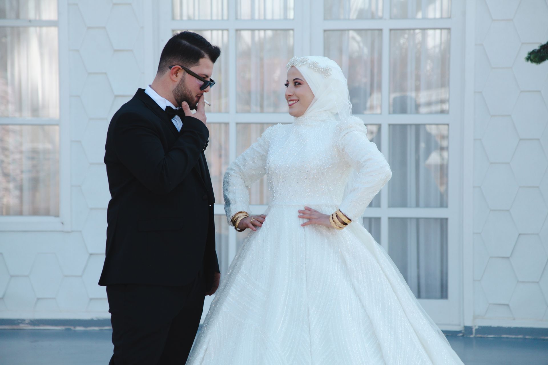 A stylish couple in wedding attire posing outdoors, showcasing elegance and joy.