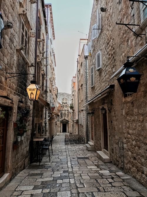Free Charming stone alleyway in historic European village lined with cafes and lanterns. Stock Photo