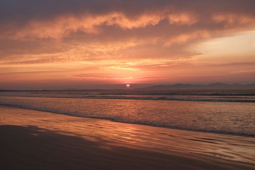 Free Breathtaking sunset over a tranquil beach with vivid skies and gentle waves. Stock Photo