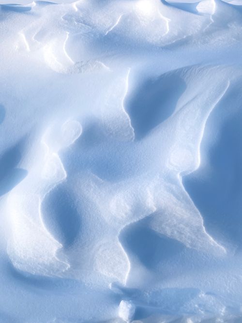 Free Detailed close-up of white snow drifts creating abstract winter patterns. Stock Photo