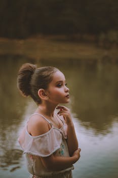 这幅肖像宁静地描绘了一位年轻女孩，她在自然光线下若有所思地摆出姿势