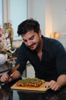 A man smiling while preparing a delicious dish in a modern kitchen.