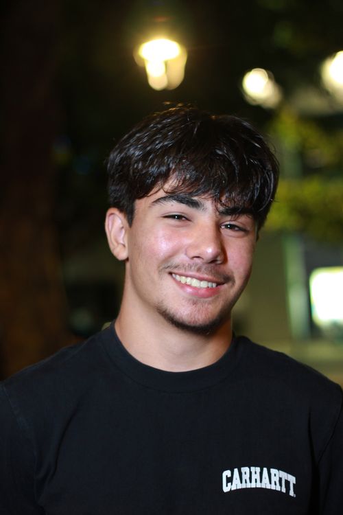 Free Portrait of a young man smiling outdoors at night with bokeh background. Stock Photo