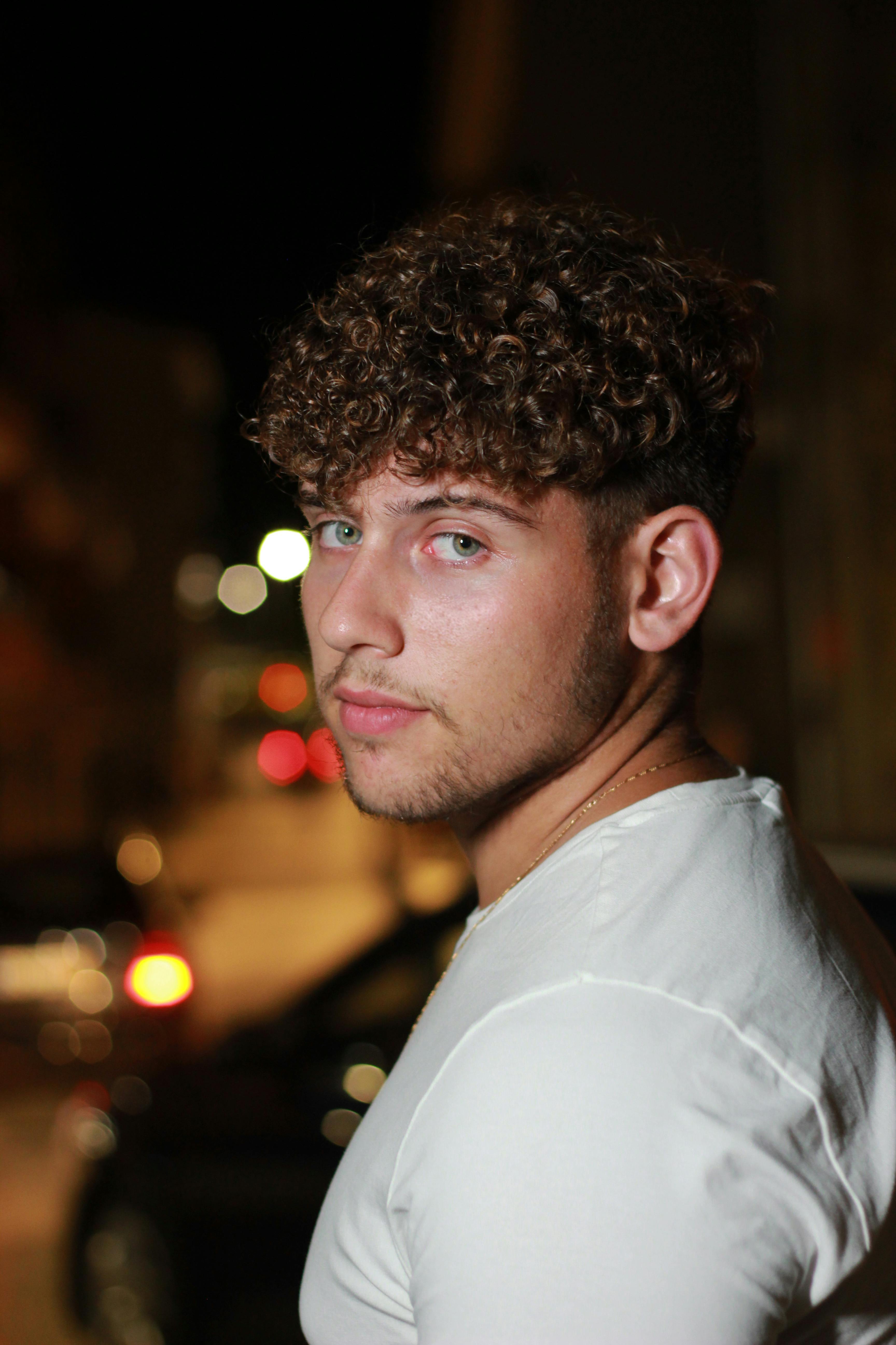 A handsome young man poses on a dimly lit street, creating a captivating night portrait.