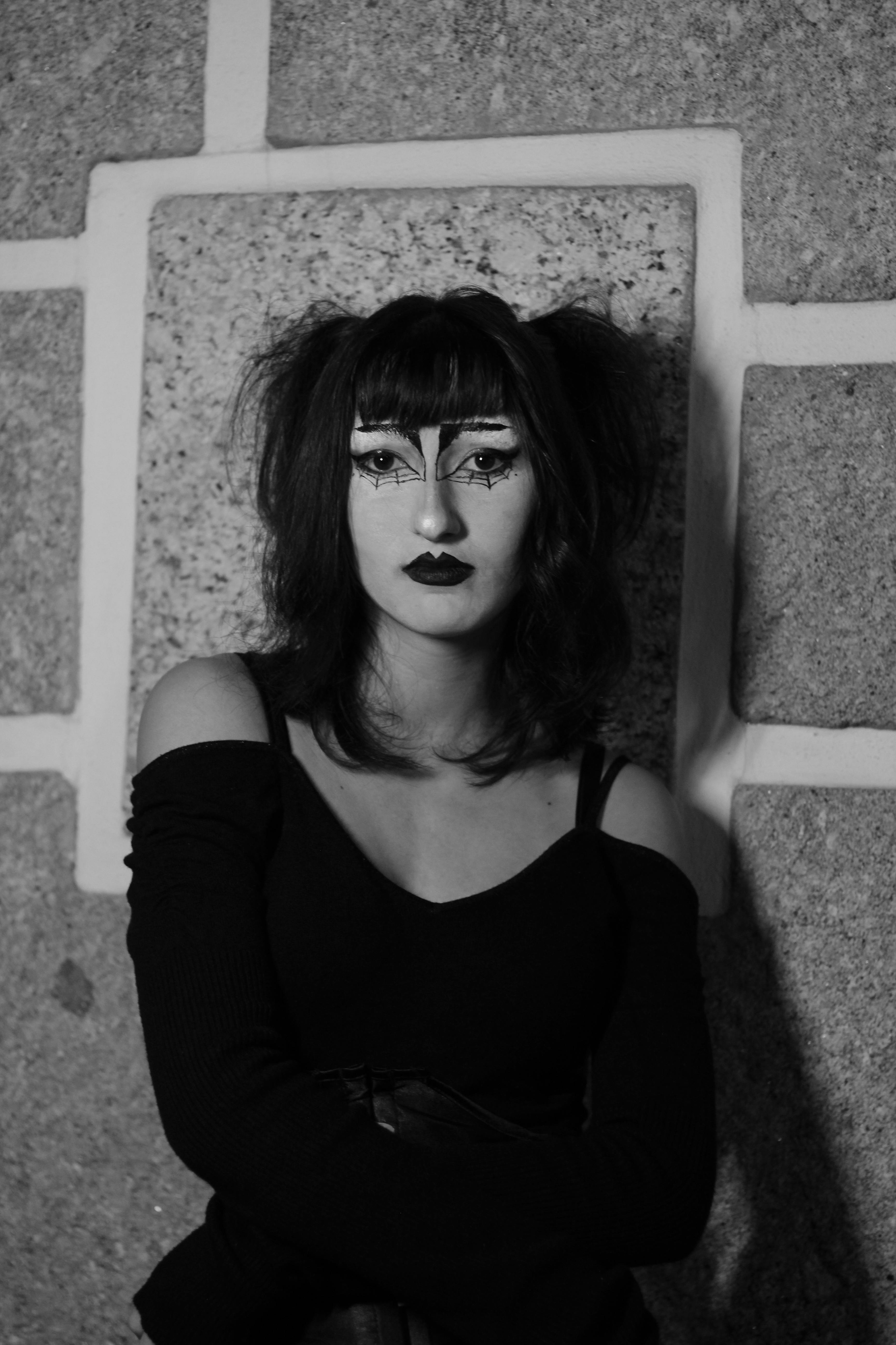 Gratuit Portrait en noir et blanc d'une femme avec un maquillage dramatique contre un mur de pierre. Photos