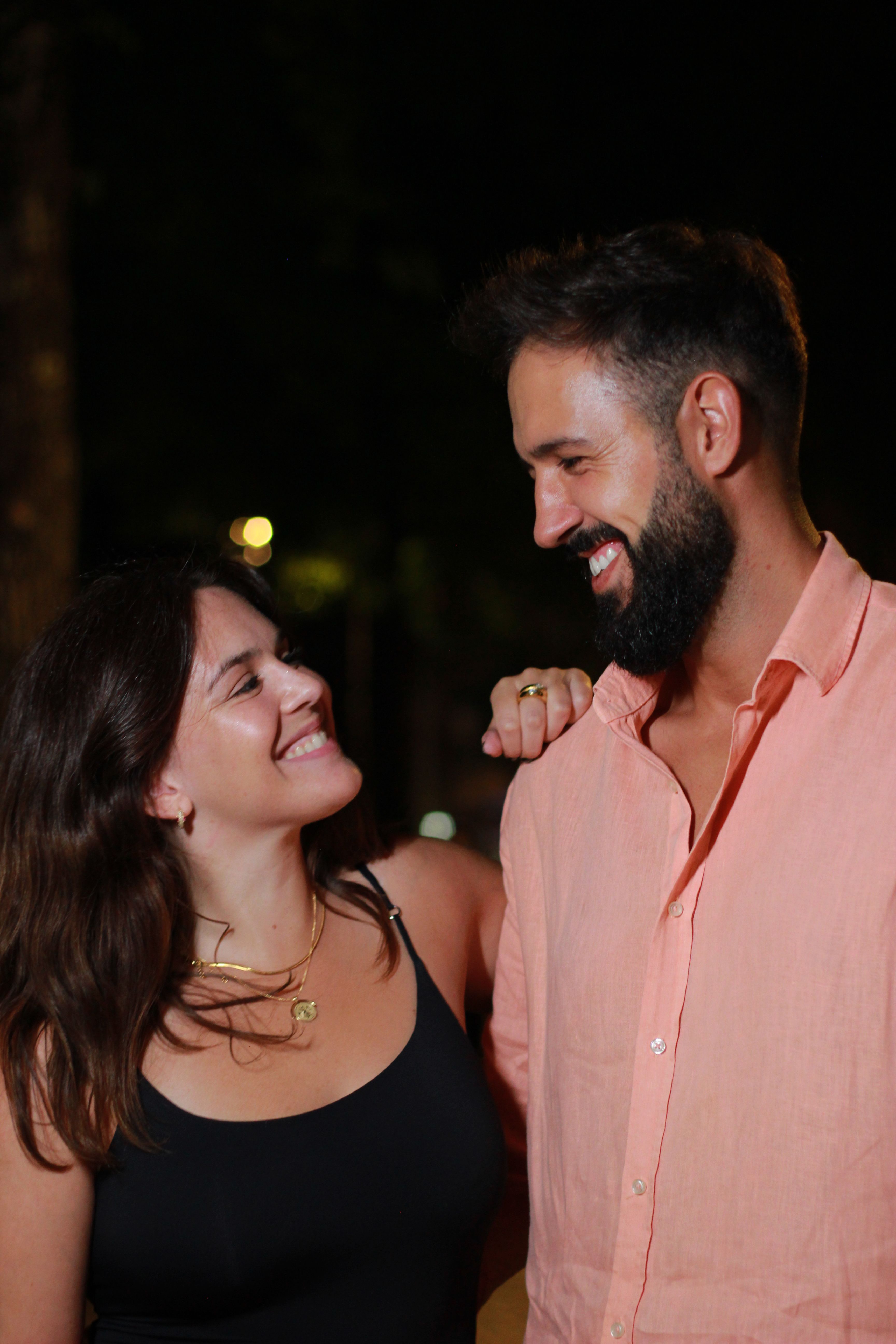 A smiling couple gazing at each other under night lights in Póvoa de Lanhoso, Portugal.