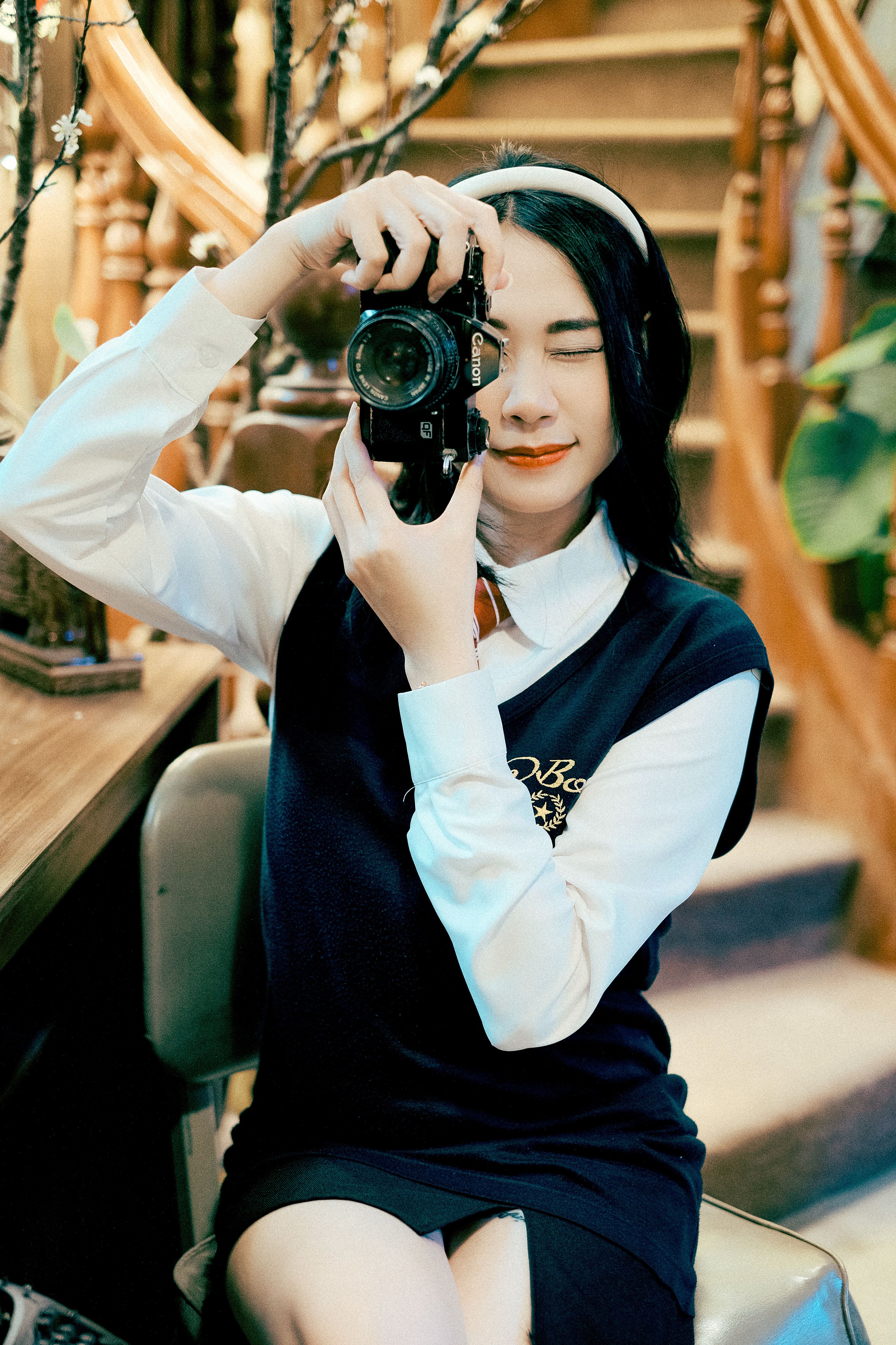 Female photographer sitting indoors capturing moments with elegance.