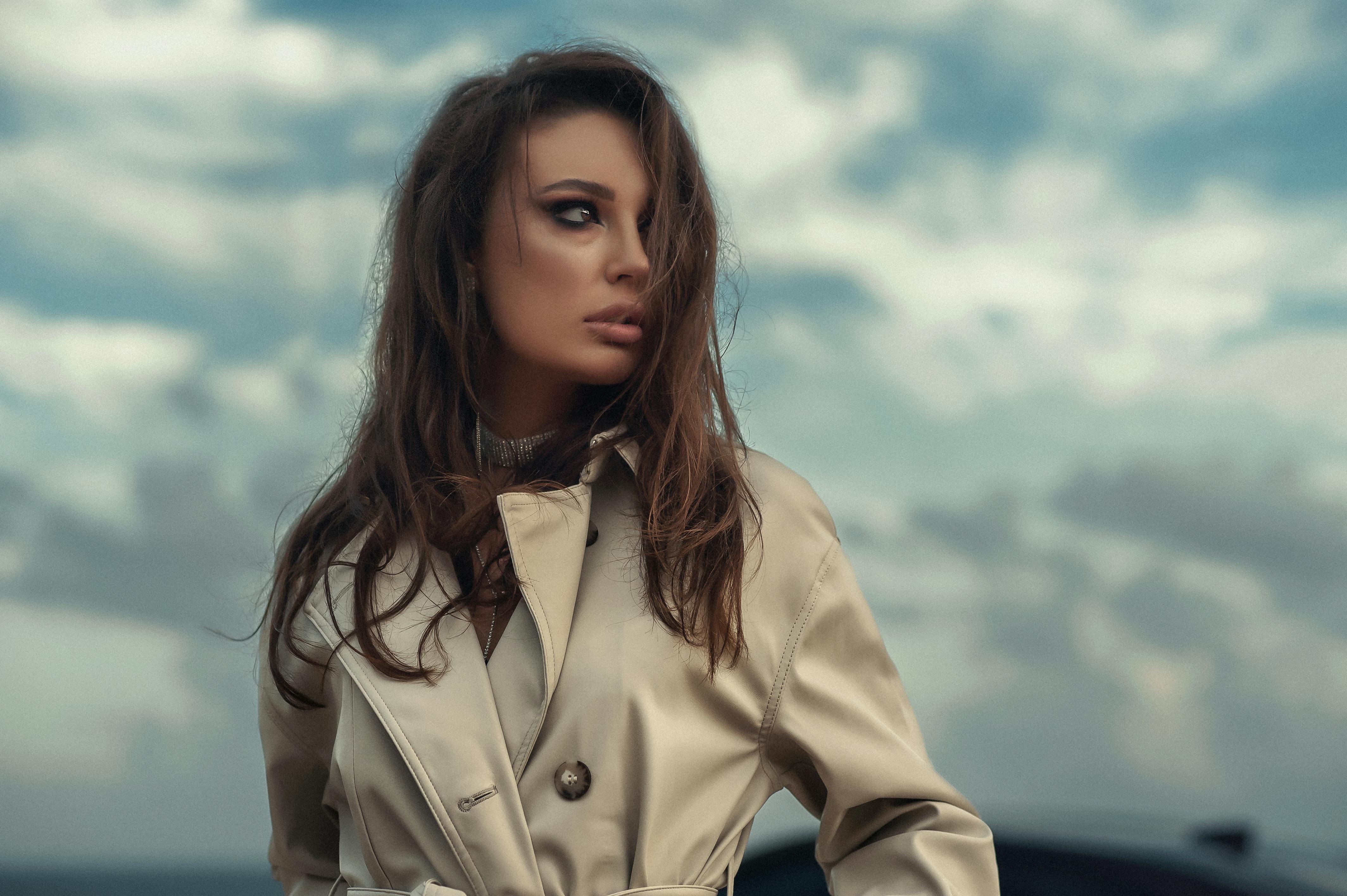 stylish woman in trench coat with windswept hair outdoors