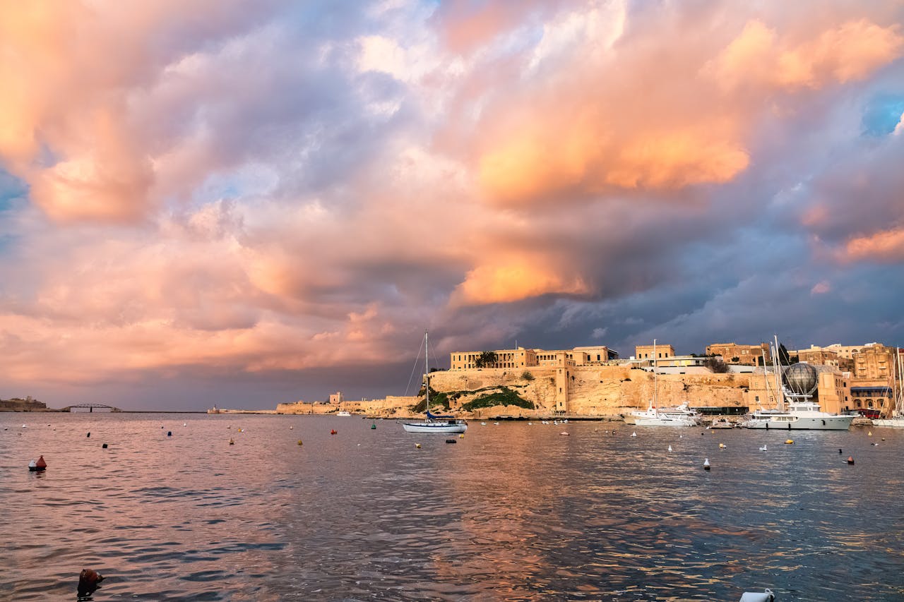 Lungomare di Valletta al tramonto con barche e riflessi sull'acqua