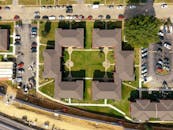 无人机视角下的对称公寓大楼，周围环绕着停车区和郊区景观