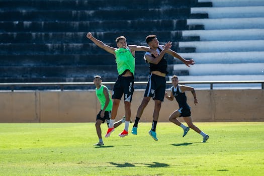 Four soccer players jump mid-air during an outdoor practice session.