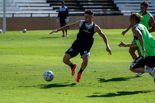Athletic men playing soccer during a training session on a vibrant green field on a sunny day.