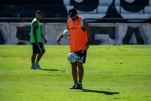Two soccer players practice on a grassy field, one controlling the ball with skill.