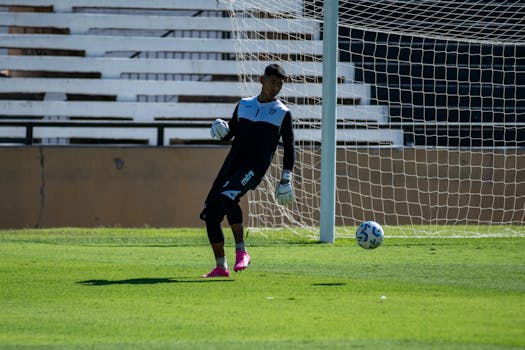 Goalkeeper kicks soccer ball on a sunny day during practice match.