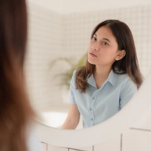 Free Woman Looking at Herself in the Mirror Stock Photo