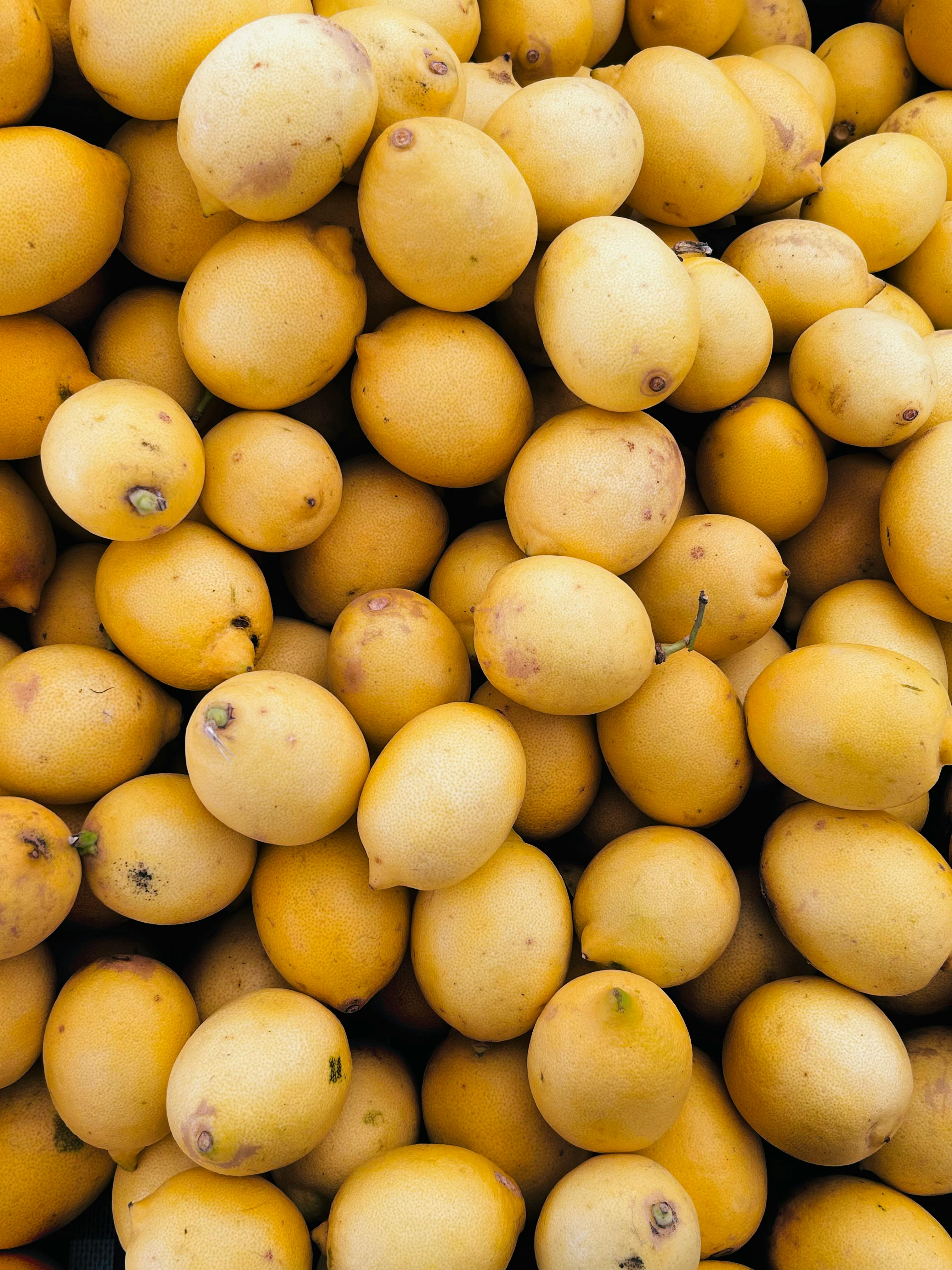 A close-up of fresh ripe lemons piled closely together, showcasing vibrant yellow colors.