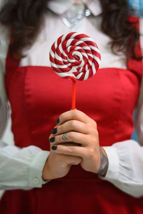 Free Close-up of a woman holding a festive red and white swirled lollipop. Stock Photo