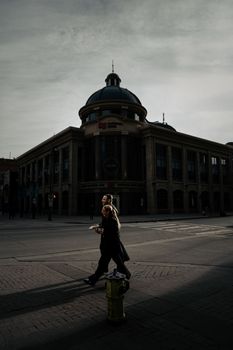 A man and woman cross the street in front of a historic building in Calgary, Alberta, Canada.