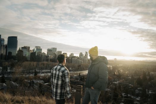 Two individuals overlooking Calgary's skyline at sunset, capturing the serene urban landscape.
