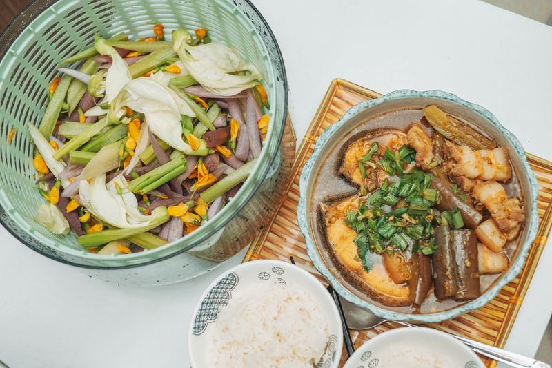 Fresh vegetable salad and traditional Asian cooked dish served with rice on a table.