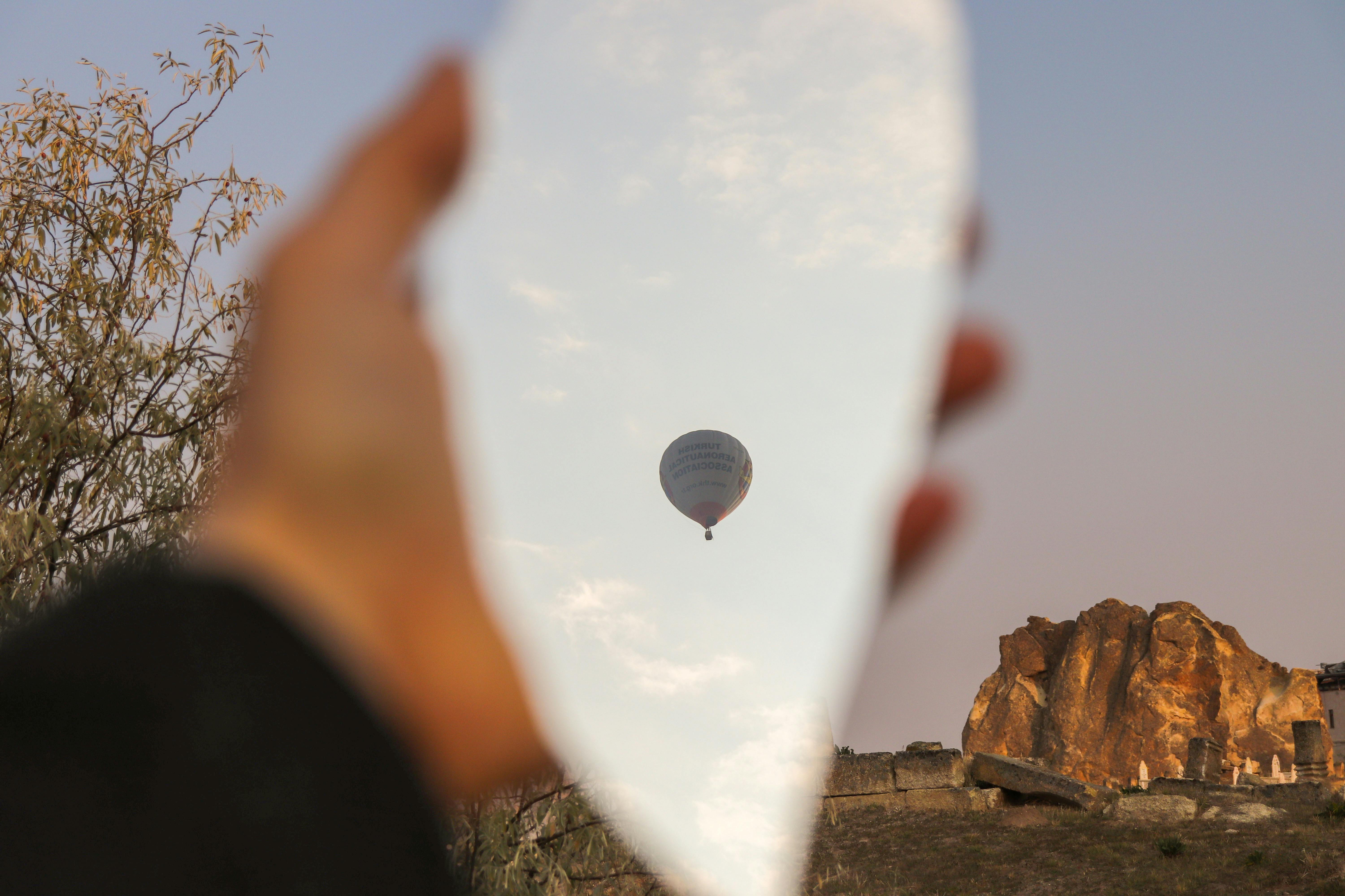 Creative view of hot air balloon reflected in a piece of broken mirror outdoors.