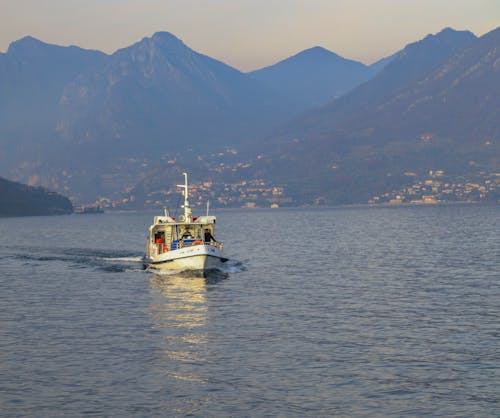 A serene view of a boat on a lake with majestic mountains in the background, ideal for travel or nature themes.