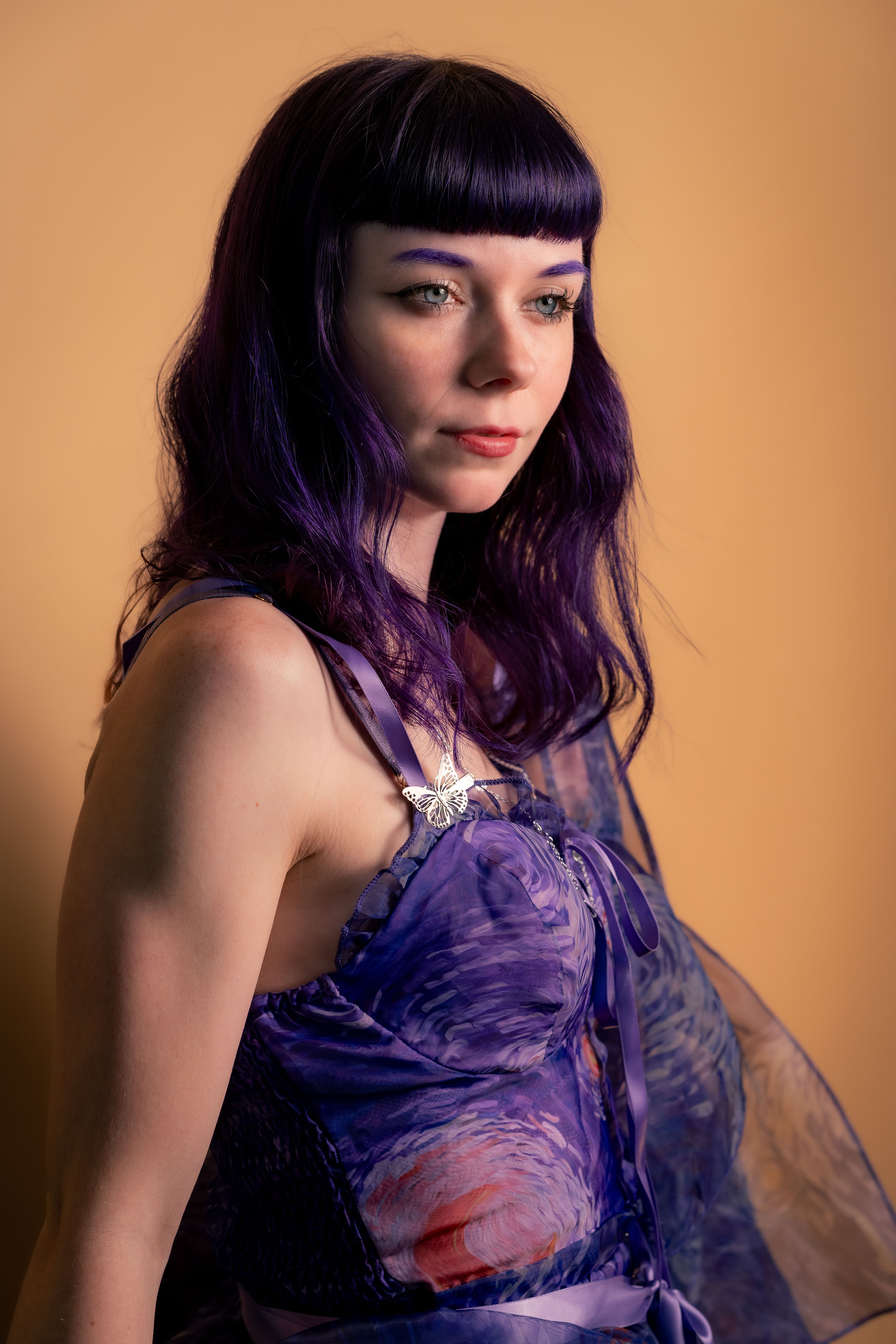 Portrait of Woman in Purple Dress with Butterfly Pendant · Free Stock Photo