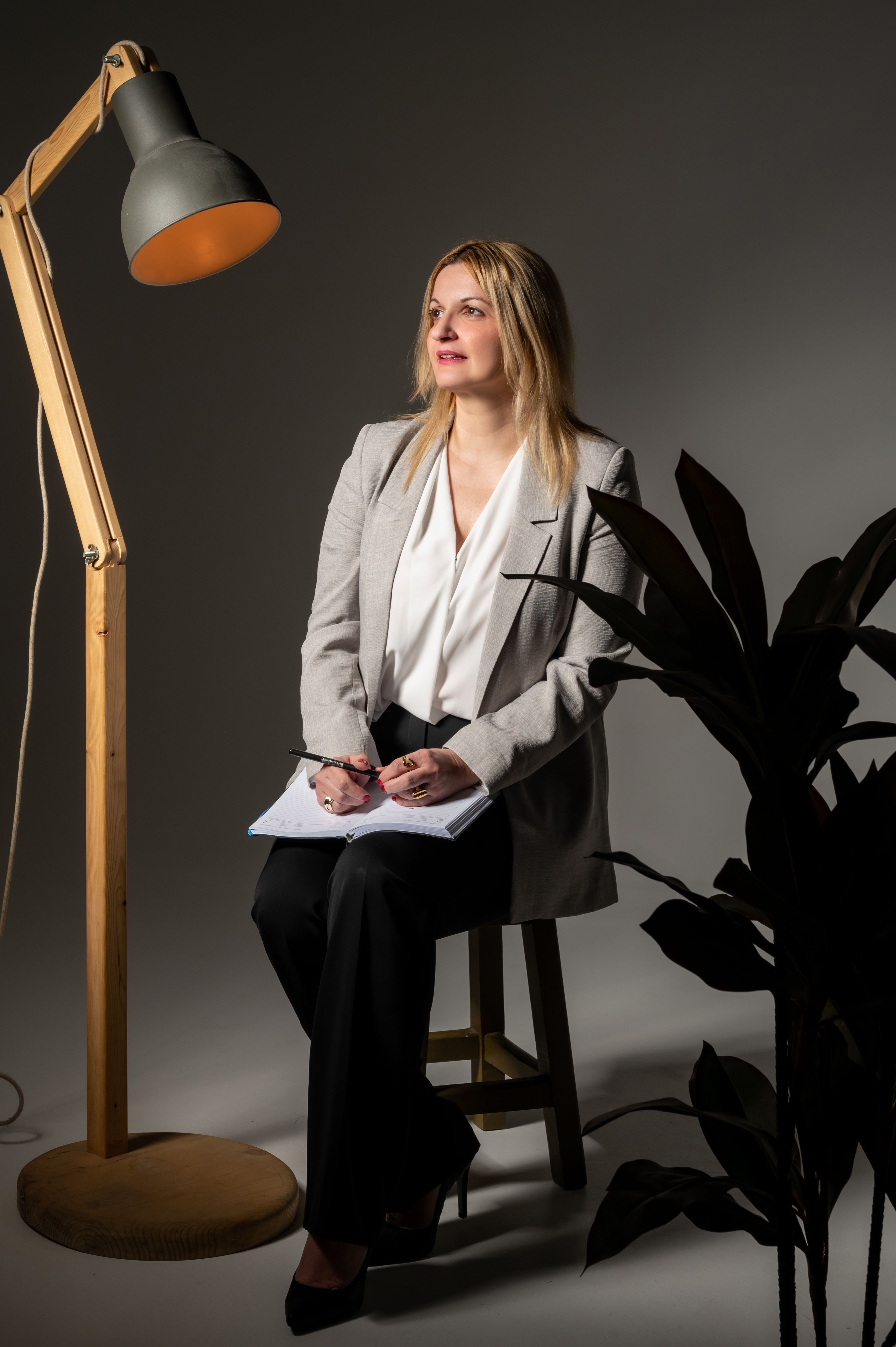 Confident businesswoman in office with a modern lamp and plant. Ideal for corporate and business themes.