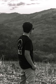 A reflective moment captured in black and white with a young man gazing over a serene landscape.