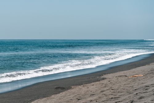 Free A tranquil sandy beach with gentle ocean waves under clear blue skies, perfect for a peaceful escape. Stock Photo