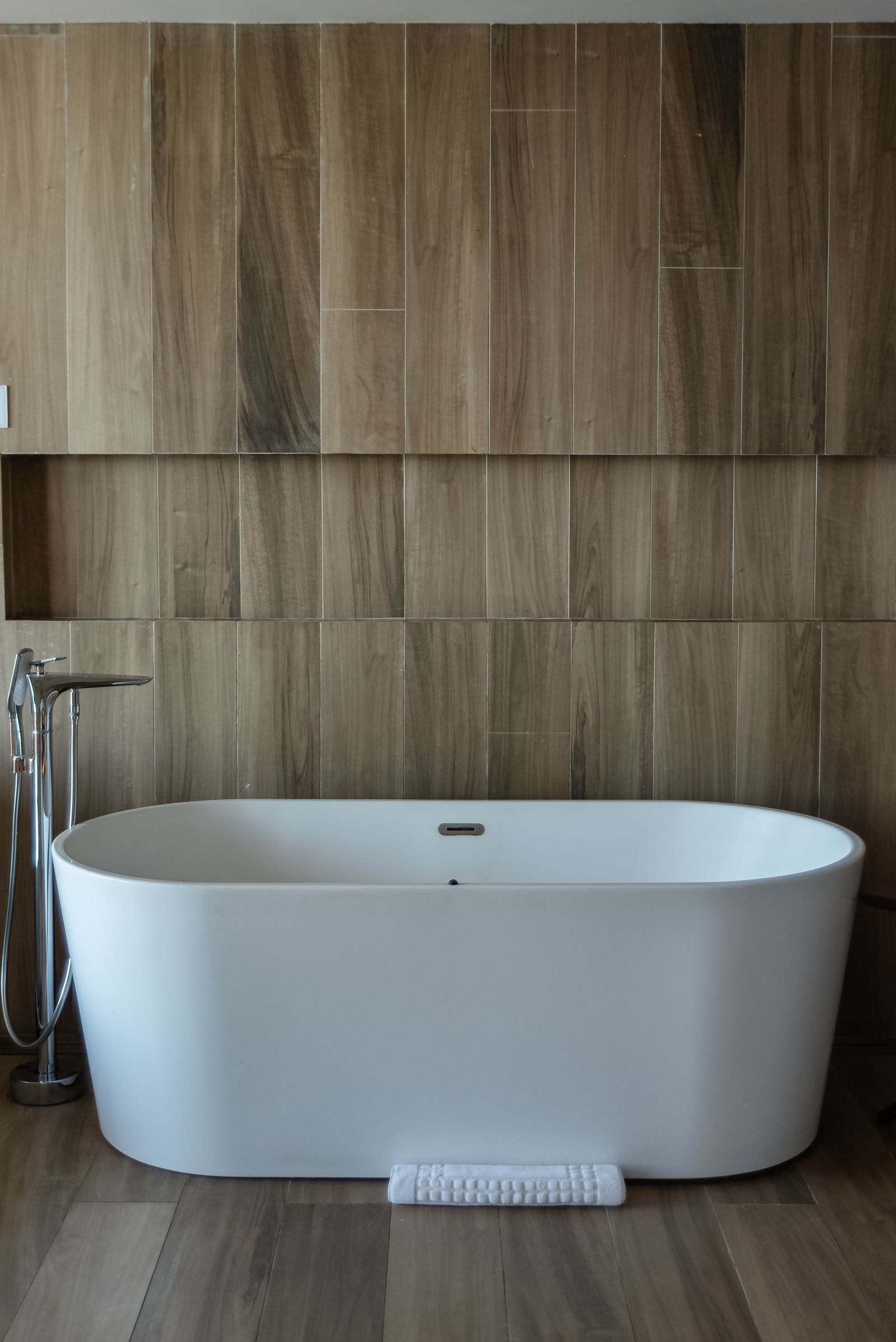 Freestanding white soaking tub in a wood-panelled bathroom