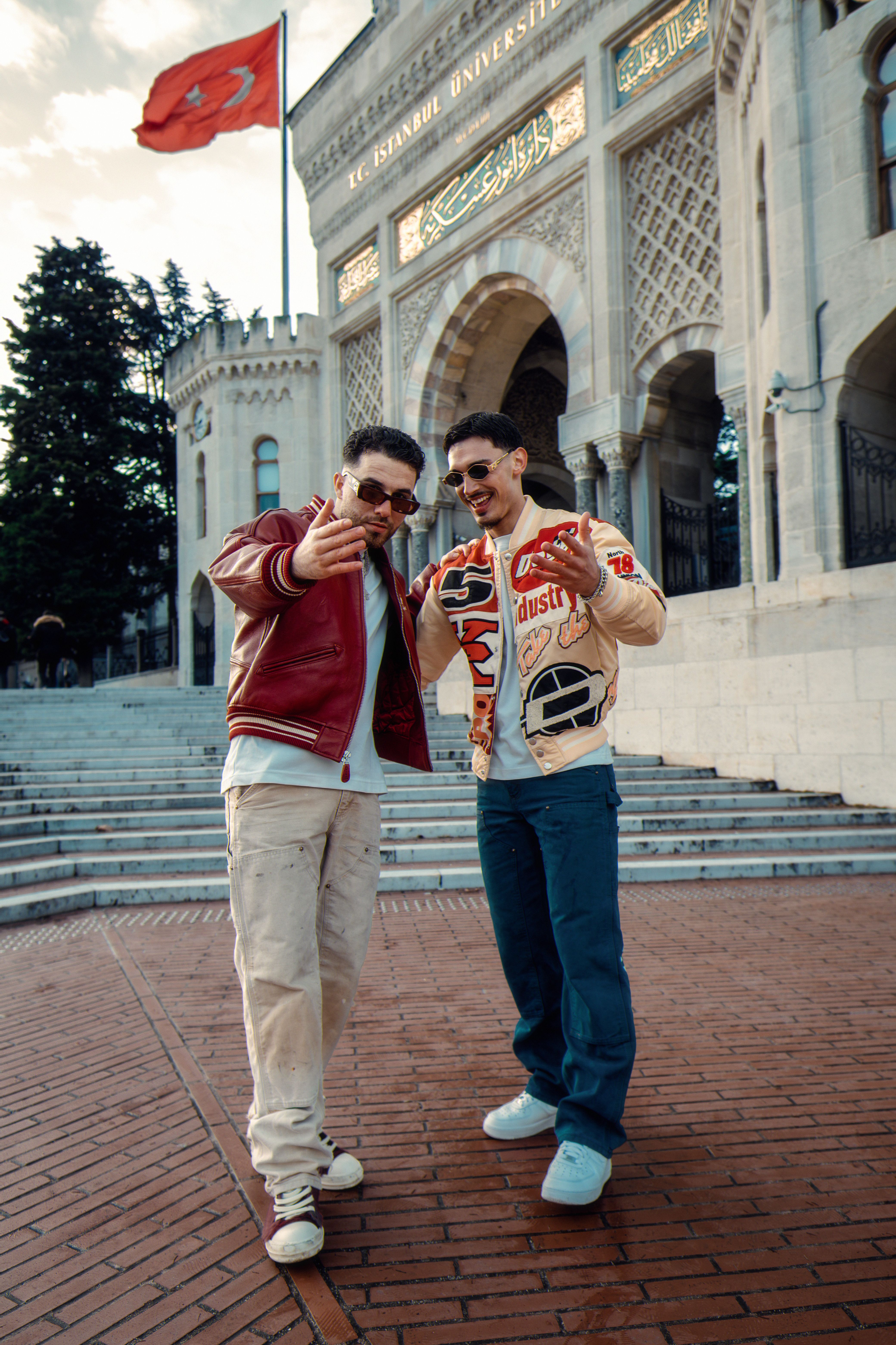 Two young adults posing happily outside the historic Istanbul University entrance.