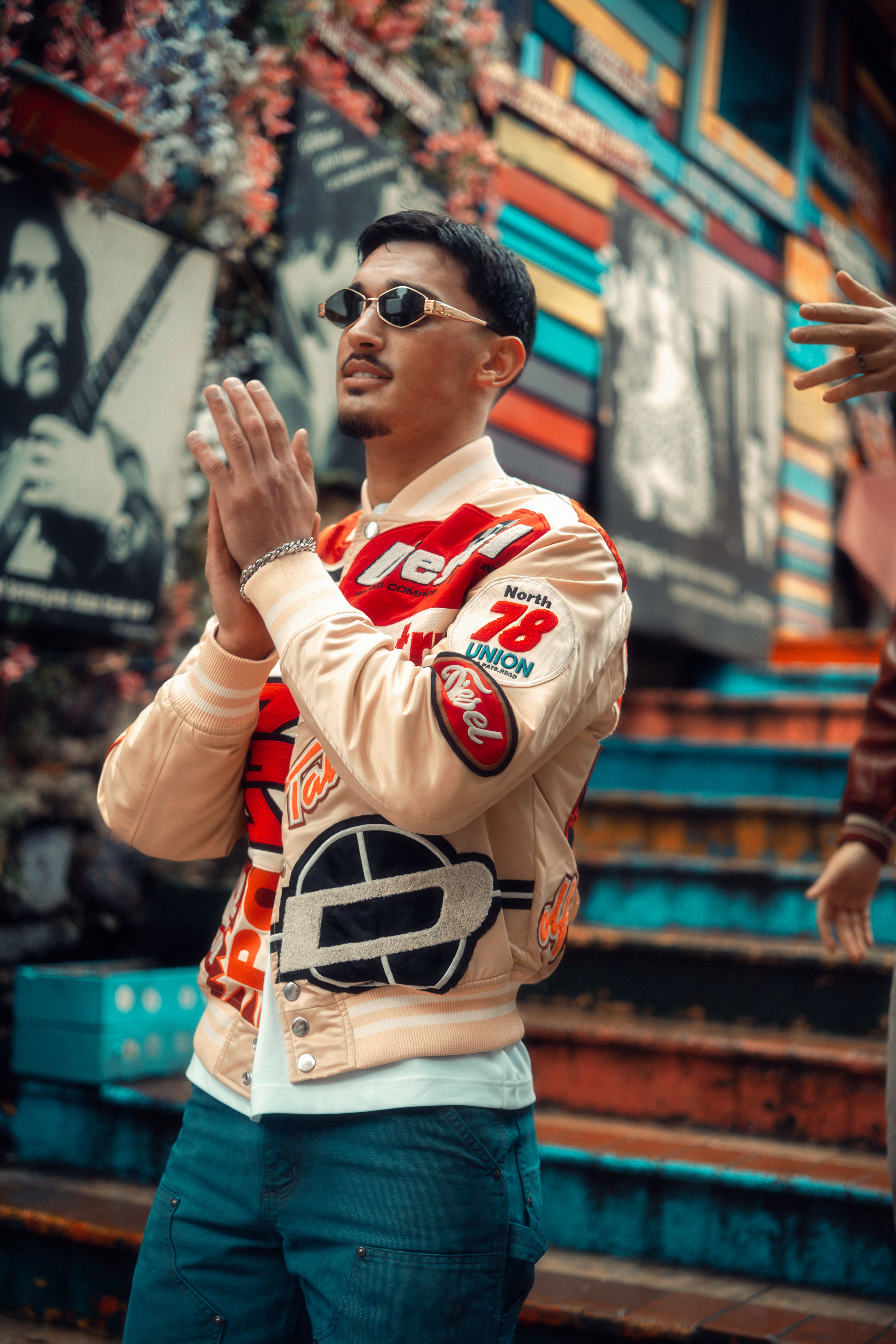 Man in urban setting wearing a stylish jacket, sunglasses, and jeans.