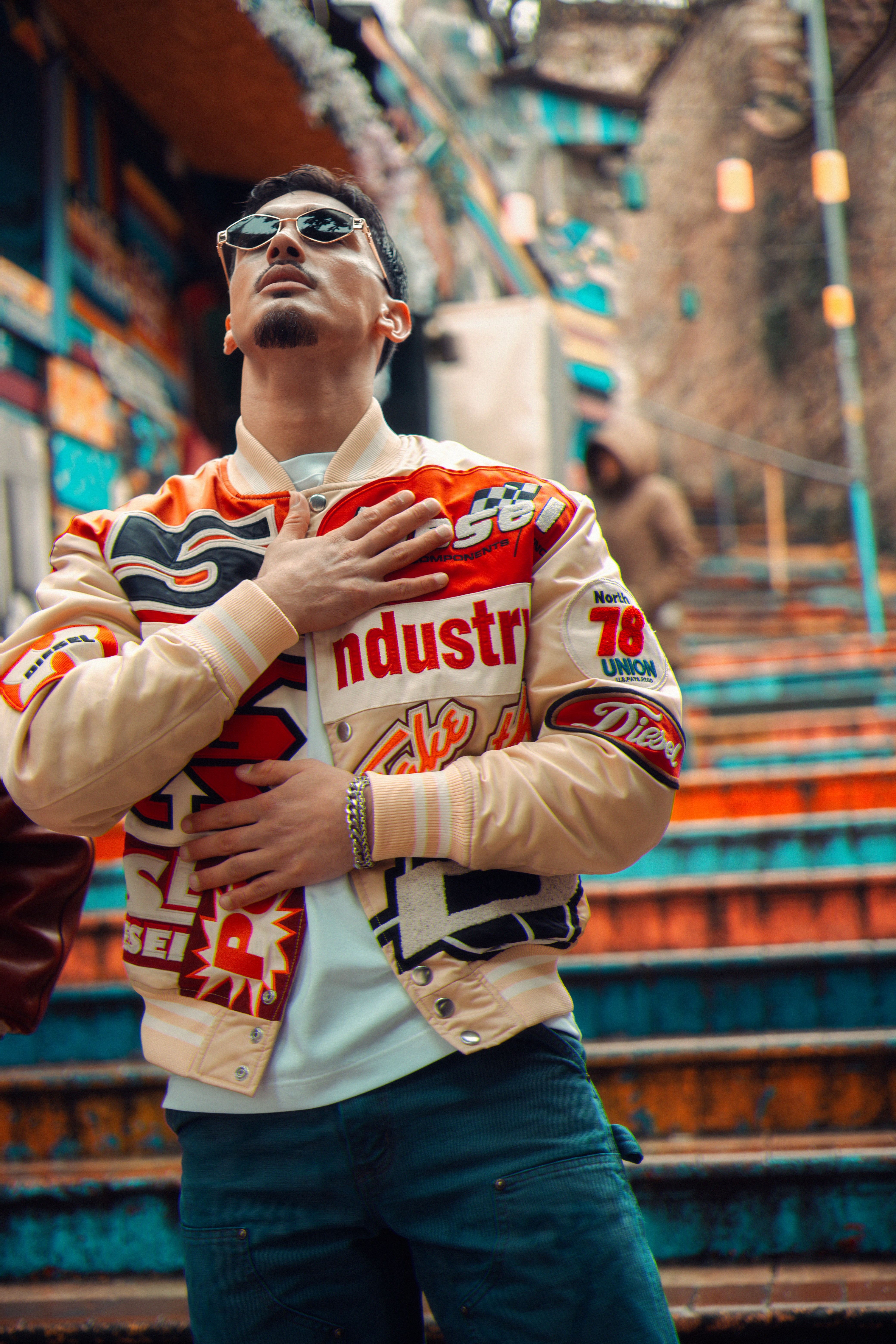 Stylish man poses on colorful staircase showcasing urban street fashion with confidence.