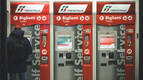 Un viaggiatore convalida il biglietto alle macchinette Trenitalia in una stazione di Firenze.