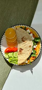 Vibrant plate of fresh vegetables, fruit, and flatbread for a healthy meal.