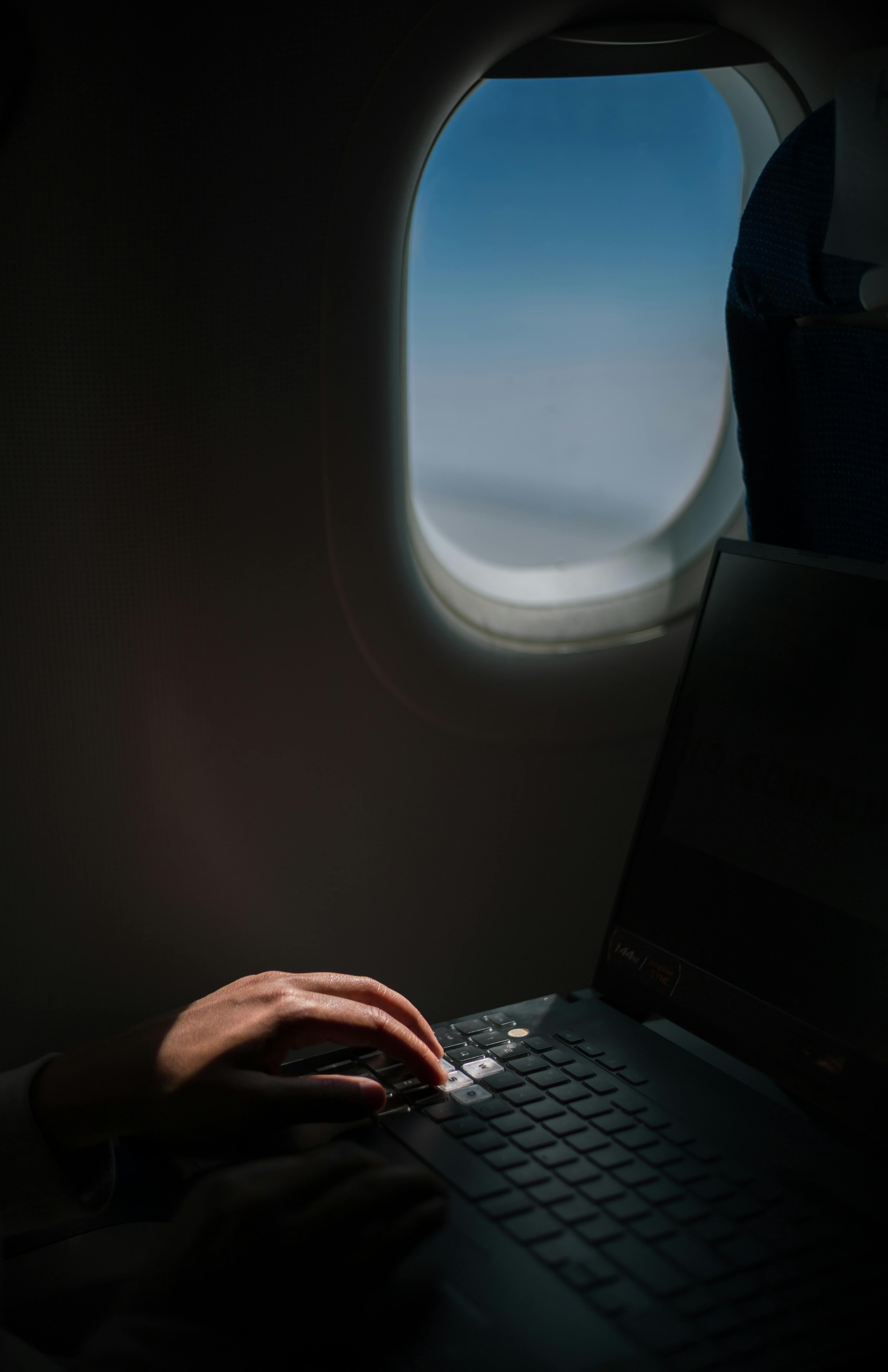 A person using a laptop while flying, showcasing productive travel habits.