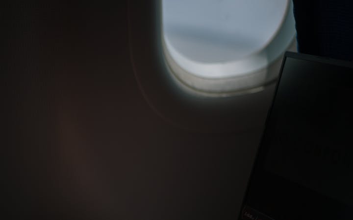 A person using a laptop while flying, showcasing productive travel habits.