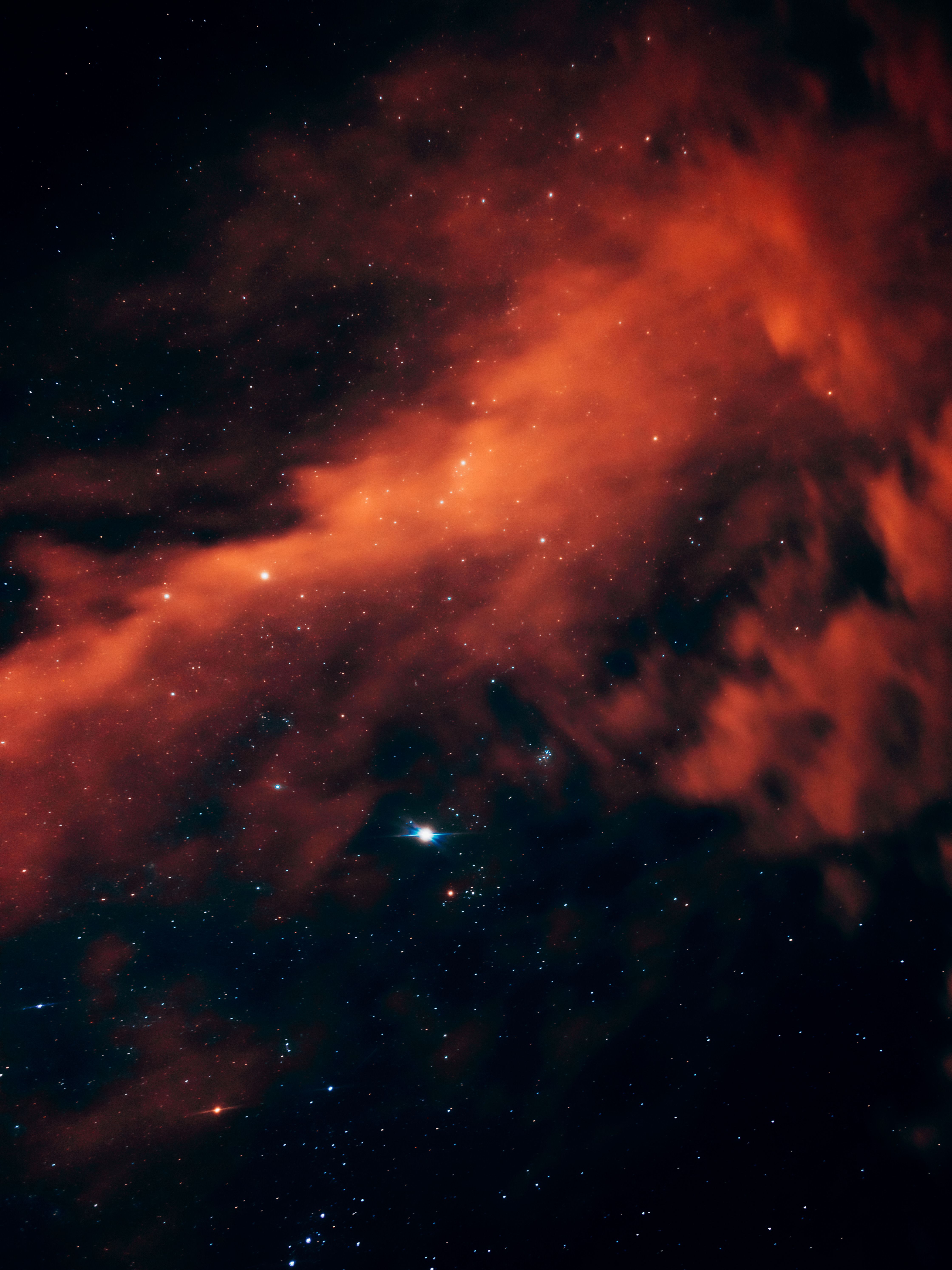 A dramatic view of a red nebula surrounded by stars, showcasing cosmic beauty.
