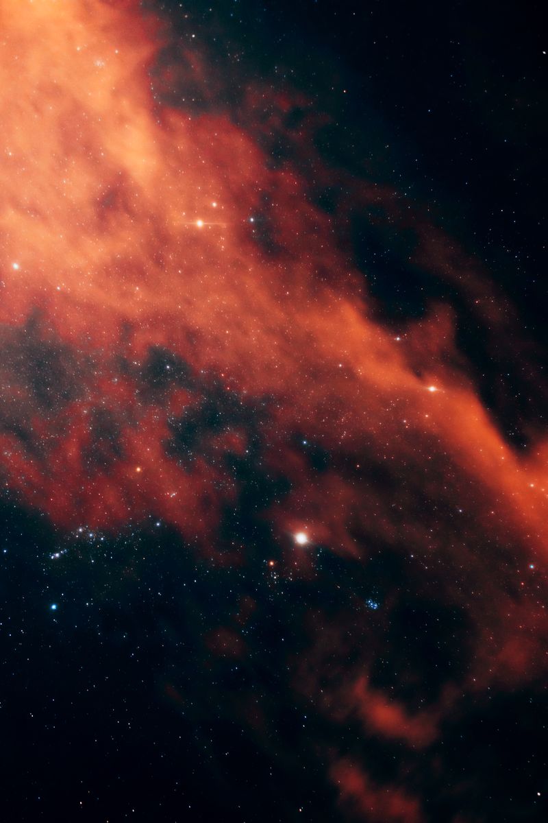 Vivid image of a red nebula with stars in the night sky creating a dramatic cosmic scene.