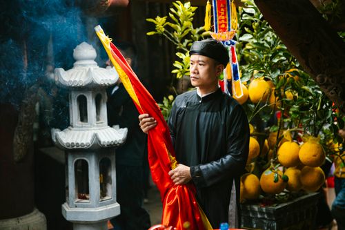 Free Man in traditional attire holding flag at cultural festival surrounded by fruit and incense. Stock Photo