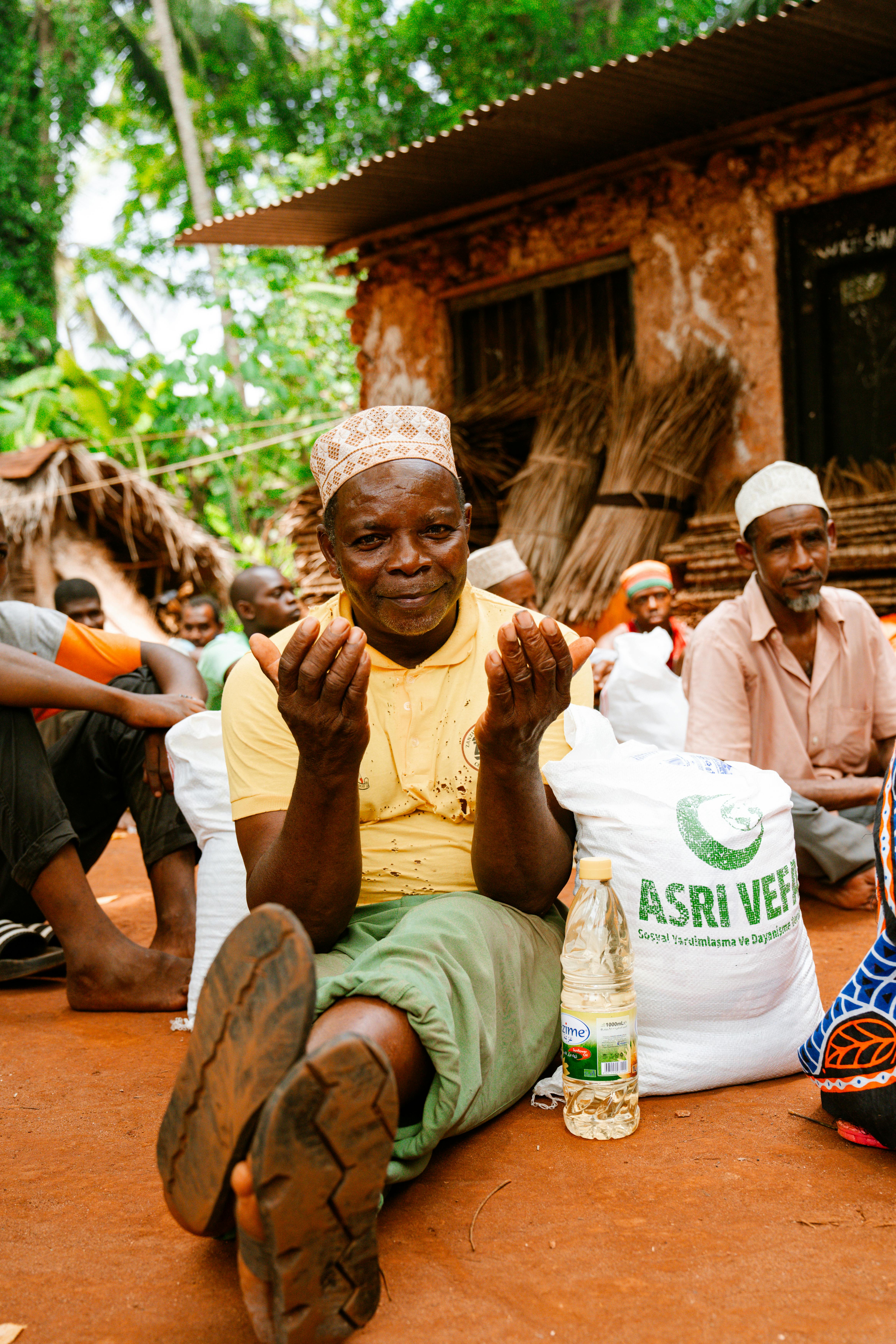 Men sitting outdoors sharing a moment in a village setting.