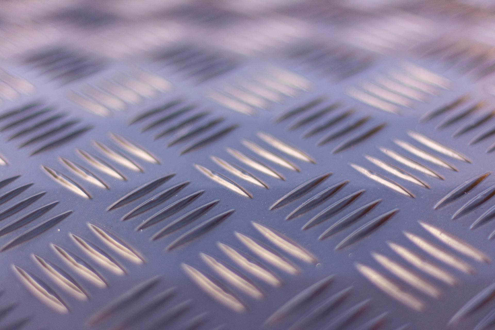 Detailed view of a checker plate metal surface showcasing its ribbed texture in soft lighting.