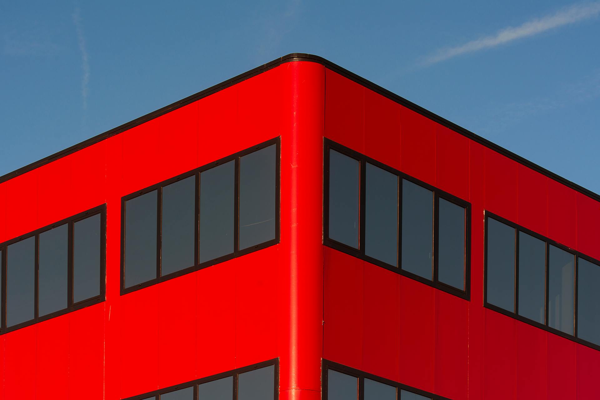 Vibrant red building façade against clear blue sky in Hoofddorp, Netherlands.