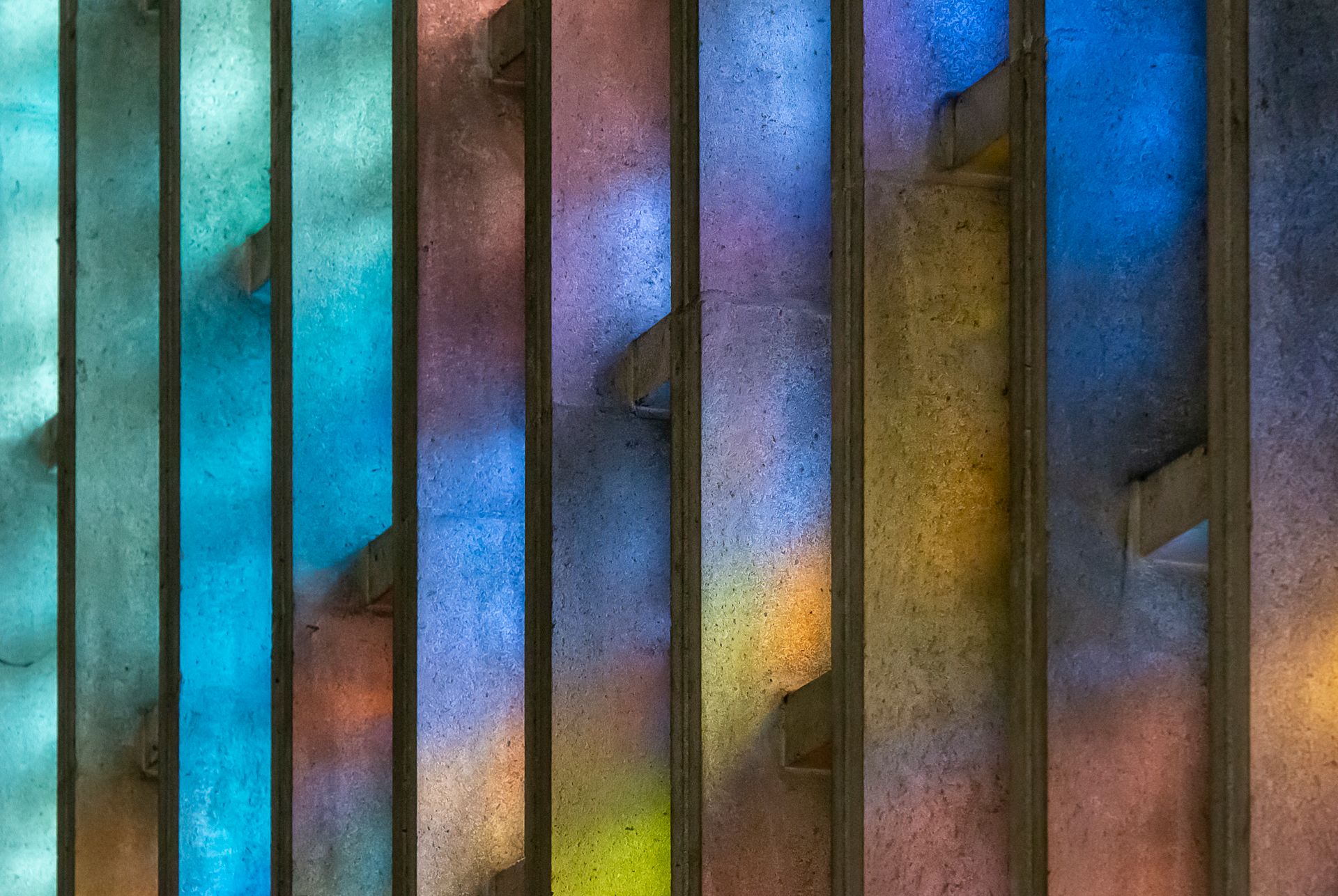 Vibrant stained glass light reflections create a colorful display on a concrete wall.